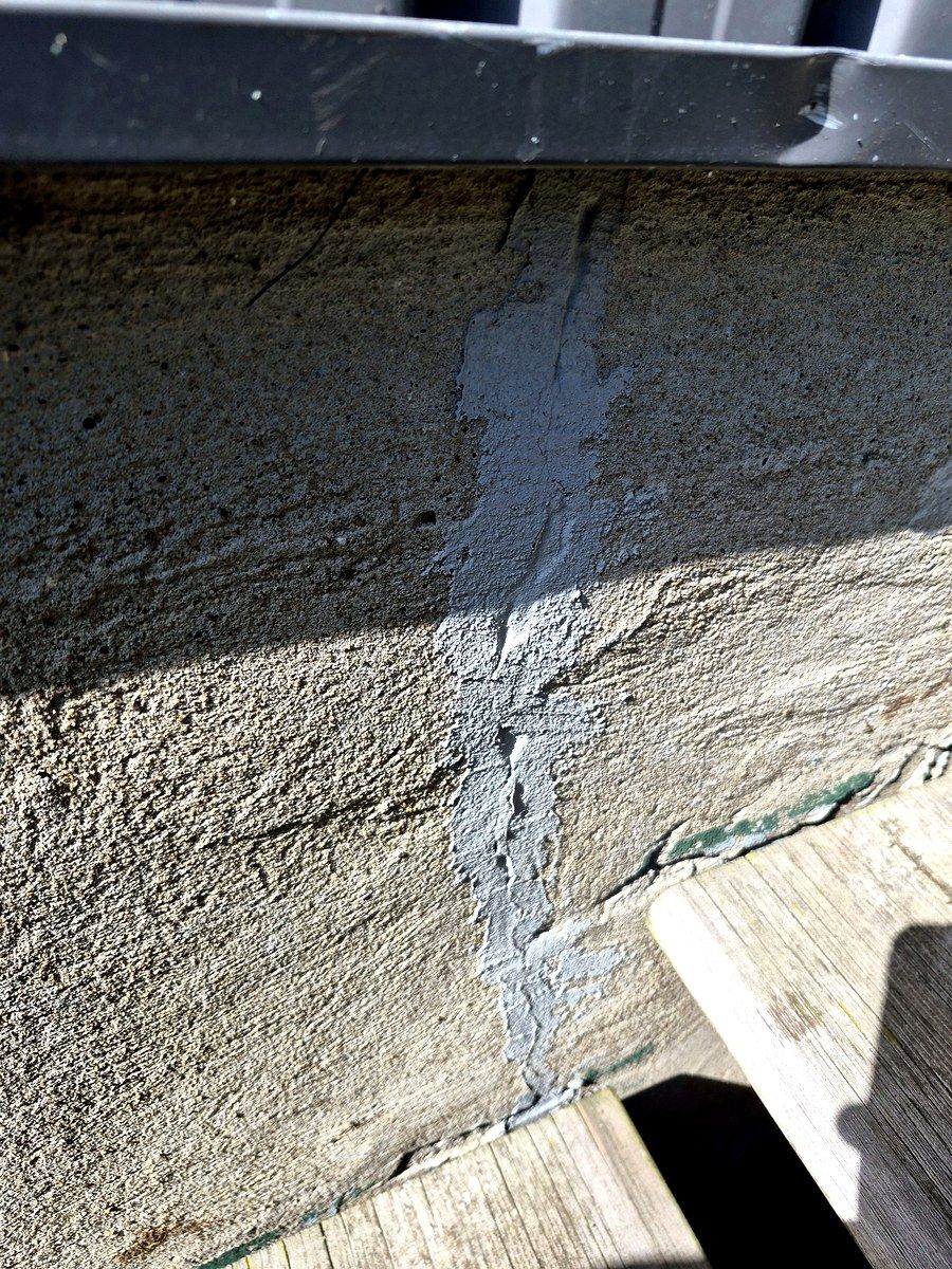 Fissure de fondation en béton colmatée au scellant — réparation à vérifier.