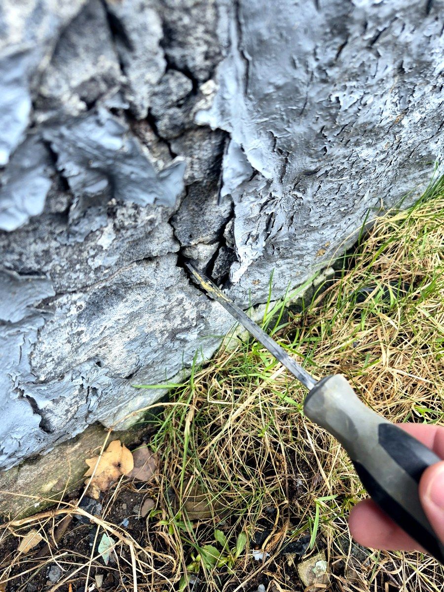 Fissure profonde dans un mur de fondation — le tournevis s'enfonce, signe de faiblesse.