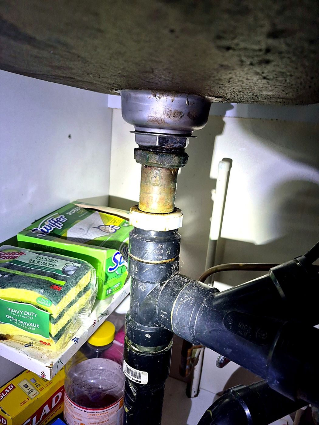 Drain d'évier en laiton corrodé raccordé à de l'ABS — un raccord à surveiller de près.